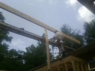 Carpenter setting a ridge beam over a new addition frame — Ice Dam Removal by Roofing Brothers in Norlina