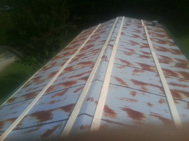 Rusted metal roof panels with new wood purlins before replacement — Storm Damage Roof Repair in Norlina by Roofing Brothers