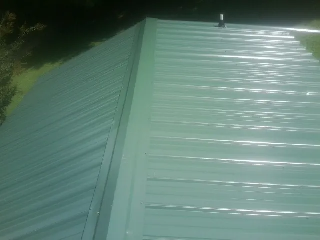 New green metal panels meeting at the ridge of a roof — Flat Roof Repair work by our crew in Norlina