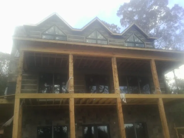 Dormers and porch framing on a large log home under construction — Roof Coating work by our crew in Norlina