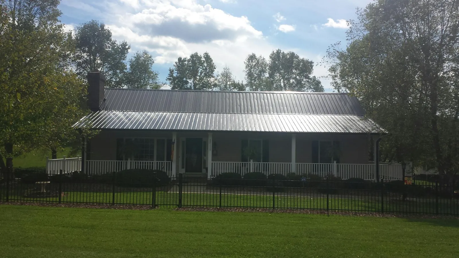 Gray metal roof on a brick ranch with a full width front porch — Gutter Guard Installation work by our crew in Norlina