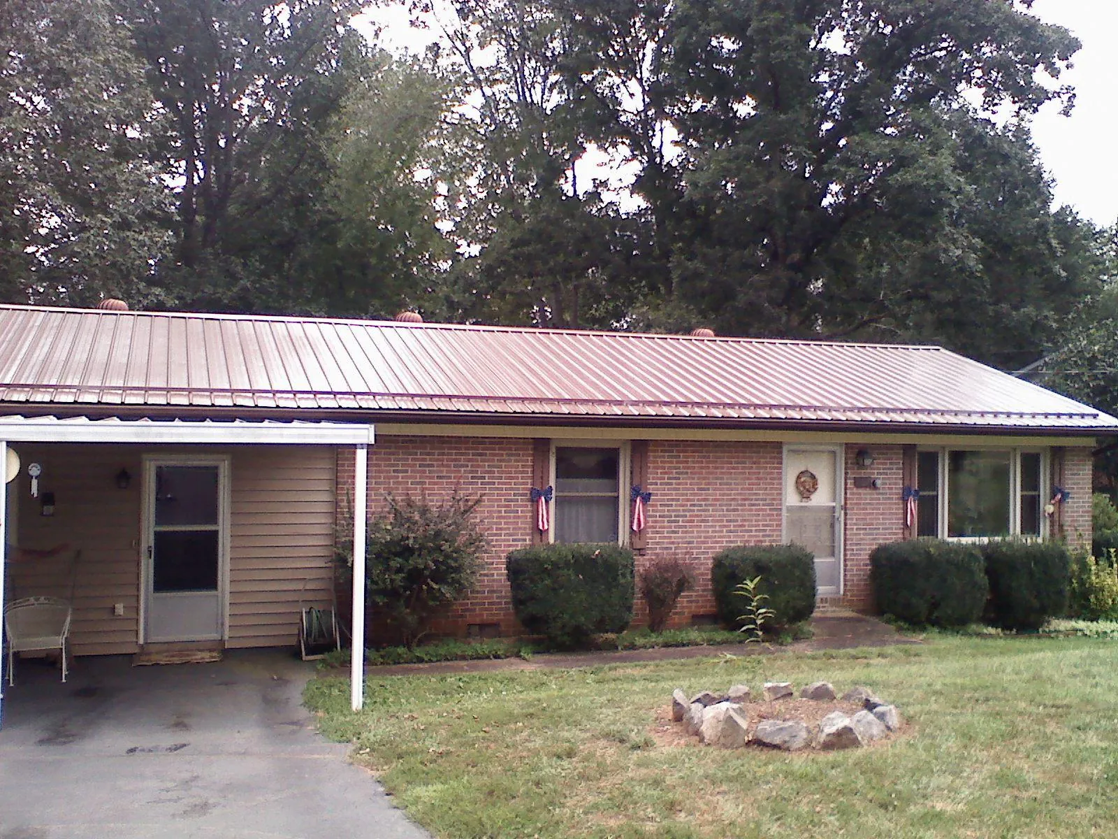 Bronze metal roof and carport on a brick ranch home — Roof Repair work by our crew in Norlina