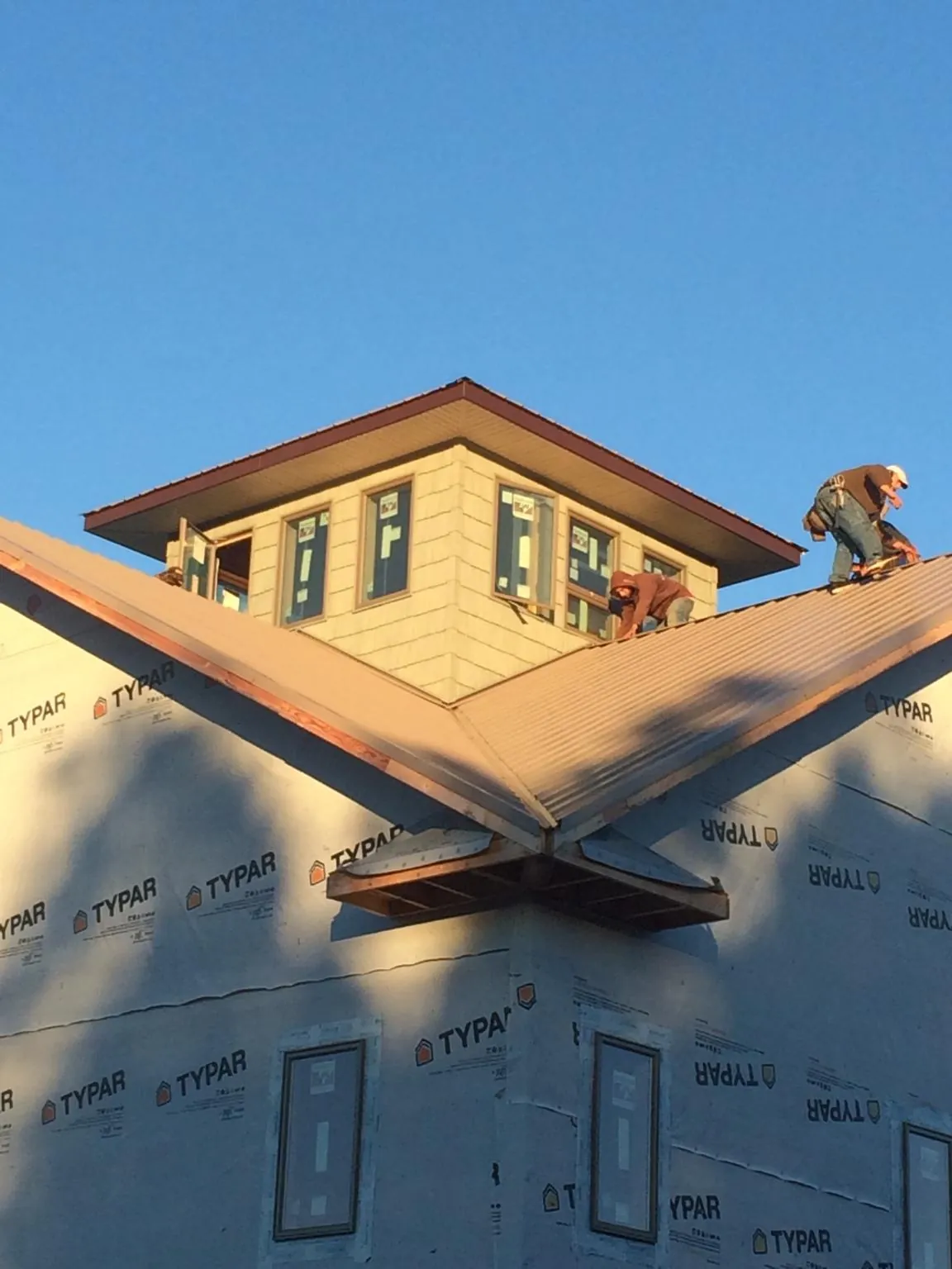 Roofers working around a rooftop cupola on a new metal roof at sunset — Roof Waterproofing in Norlina by Roofing Brothers